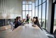 © YiuCheung - A group of business professionals are gathered around a conference table, applauding a colleague who is standing and smiling.