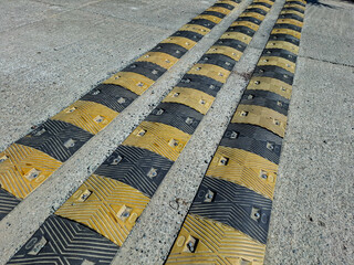 The three yellow and black speed bumps function to force the vehicle to reduce speed