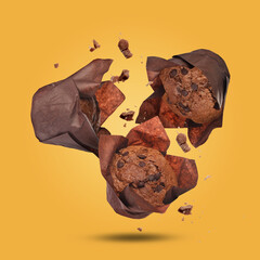 Wall Mural - Delicious chocolate muffins and crumbs falling on golden background