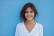 © Surachetsh - Smiling brightly, a Caucasian woman in a white shirt poses confidently against a turquoise backdrop, highlighting her charm and beauty.