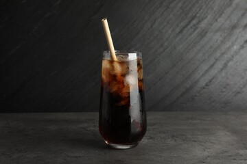 Tasty refreshing drink with straw in glass on grey textured table