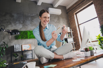 Photo of adorable positive lady broker wear shirt eyeglasses sitting table enjoying video game gadget indoors workplace workshop