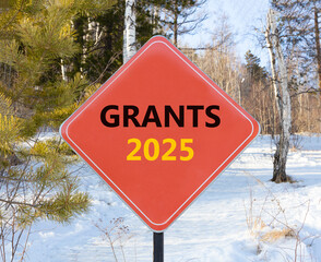 Planning grants 2025 new year symbol. Concept words Grants 2025 on beautiful red road sign. Beautiful winter forest background. Business grants 2025 new year concept. Copy space.