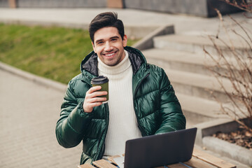 Poster - Photo of cheerful handsome man sitting on cafe terrace enjoying relax rest autumn day outdoors