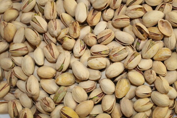 Close-up view of a pile of shelled and unshelled pistachios, showcasing their textures and colors in natural light