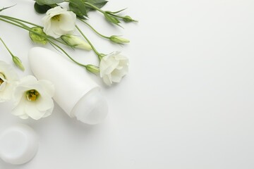 Wall Mural - Roll-on deodorant and beautiful eustoma flowers on white background, flat lay. Space for text