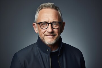 Portrait of a handsome senior man in eyeglasses over grey background.