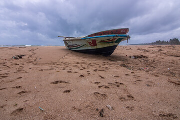 Beach, with a boat and a view of the sea in the evening at sunset. Landscape with clouds in Induruwa, Bentota Beach, Sri Lanka, India, Asia