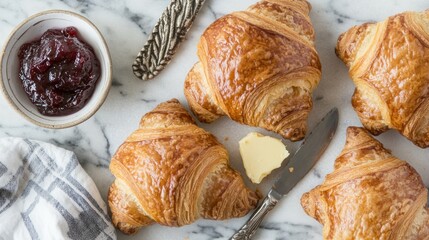 Canvas Print - Freshly baked croissants with butter and jam on a marble surface.