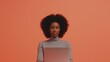 © Ben Trobat - Woman with natural hair using a laptop against an orange background
