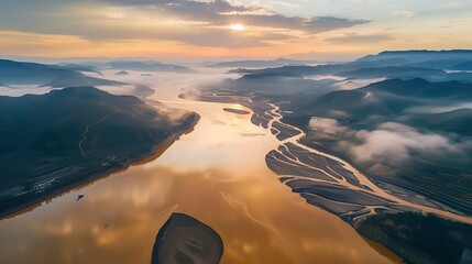 Aerial view of a river winding through a valley with mountains in the background, under a cloudy sky.