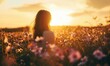 © bernd77 - Woman standing in a field of flowers during golden hour