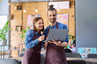 © Valerii Honcharuk - Young man and woman workers owners in aprons using laptop, inside restaurant cafe