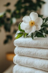 Poster - A stack of white towels with a single flower on top, ideal for bathroom or spa settings