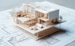 © Curioso.Photography - A detailed architectural model of a modern house placed on top of blueprints, highlighting design and planning stages.