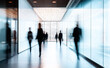© Curioso.Photography - Motion blur of businesspeople walking through a modern office hallway with glass walls.