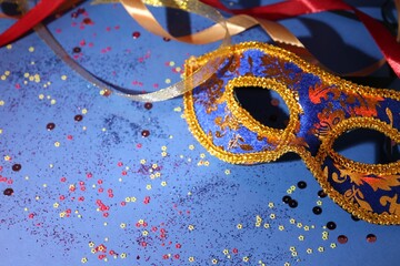 Wall Mural - Beautiful carnival mask, ribbons and confetti on blue background, closeup