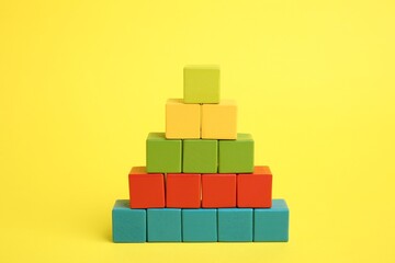 Canvas Print - Pyramid of colorful cubes on yellow background