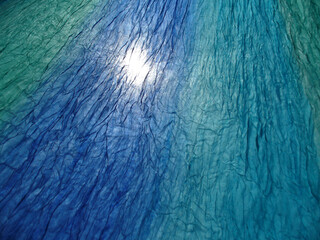 Aufkleber - Delicate, airy, blue and turquoise material wrinkled in wind and sunlight - abstract background. Topics: texture, pattern, weather, wind, atmosphere, season, sunny season, vacation, relaxation, rest
