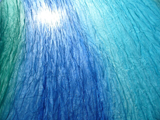 Aufkleber - Delicate, airy, blue and turquoise material wrinkled in wind and sunlight - abstract background. Topics: texture, pattern, weather, wind, atmosphere, season, sunny season, vacation, relaxation, rest