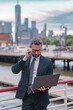 © Volodymyr - Middle eastern millennial business man in suit working on laptop outdoor. Mature handsome businessman working on his laptop outside in NY. Confident Entrepreneur using PC on the street.