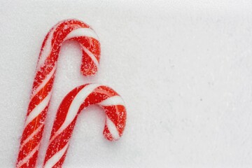 Festive red and white candy canes on snowy background