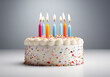 © Flashworks Stock - Birthday cake with colorful candles and sprinkles sits on a white background.