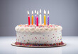© Flashworks Stock - Birthday cake with colorful candles and sprinkles sits on a white background.