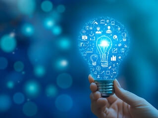 Poster - A hand holds a lightbulb with a bright light and small icons around it against a blue bokeh background
