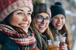 © Asier - Three young women in winter clothes drinking mulled wine and smiling.