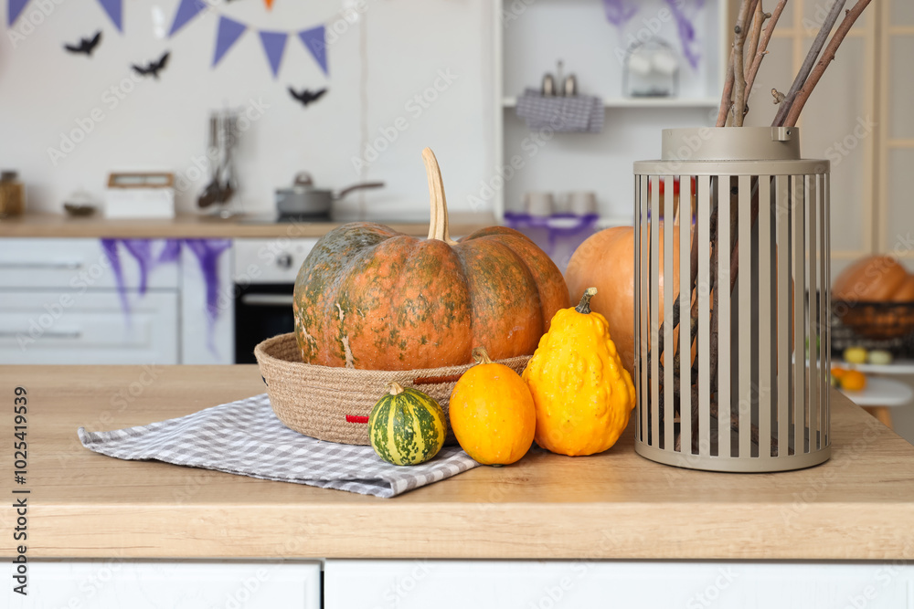 Vase with tree branches and Halloween pumpkins on counter in kitchen
