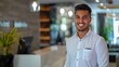 © AounMuhammad - Smiling receptionist in uniform standing confidently at her workspace, embodying professionalism and a welcoming atmosphere in customer service