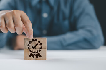 Poster - Quality warranty concept. Man's hand puts the wooden cubes with quality warranty icon on wooden cubes with grey background. Used for banner and advertising product and service quality commitment.