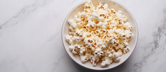 Poster - A white bowl filled with popcorn against a white marble background.