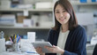 © boxstock production - Smiling Asian businesswoman holding a digital tablet in a bright office environment