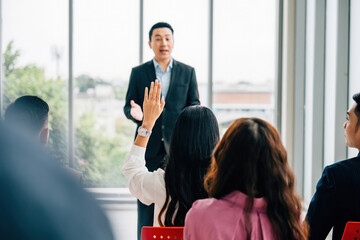 In a corporate setting, business professionals in a conference raise their hands for questions, voting, or volunteering, showcasing teamwork and active audience participation.