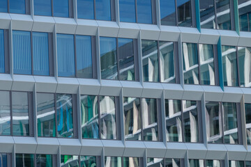 A close-up view of a modern building facade featuring a geometric pattern of blue and white panels with rectangular windows. 