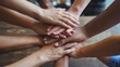 © Thanapipat - Diverse hands stacked together on a wooden table, symbolizing unity and teamwork.