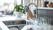 © Imsuniyah - Kitchen sink with running water, glasses being washed with soap suds