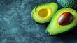 © Po - Close-up of a ripe avocado cut in half on a dark textured background, showcasing the seed and vibrant green flesh.