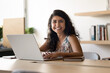 © fizkes - Happy young Indian business woman in casual posing for portrait at workplace, sitting at laptop, looking at camera, smiling, laughing, using computer for work communication in co-working space