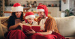 © Flashizzle/peopleimages.com - Christmas, family and happy on couch with book, funny storytelling or reading together. Parents, child and support in home with novel, literature humor and love at festive season with comedy on sofa