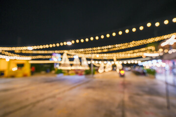 Blurred string bulb lights hang on outdoor posts at night, commonly used for Christmas and other holidays.