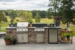 © kornc - A large outdoor kitchen with a grill, sink, and refrigerator