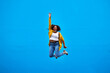 © Sanc/peopleimages.com - Jump, black woman and excited with celebration mockup in studio with winner smile. Happy, energy and African person with promotion, blue background space and leap from deal or sale announcement promo