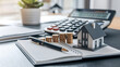 © Rsquare stock - tax day background,House model, house placed on a white surface, next to a calculator, a pencil, and some coins, symbolizing home finances, budgeting, or real estate planning.