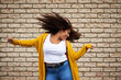 © Sanc/peopleimages.com - Excited, woman and dancing with hair flip for playful movement, energy and fun celebration of fashion winner. Happy, girl and rhythm for success, freedom and deal achievement on brick wall background