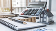 © Rsquare stock - tax day background,House model, house placed on a white surface, next to a calculator, a pencil, and some coins, symbolizing home finances, budgeting, or real estate planning.