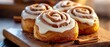 © Viktor - Cinnamon rolls with icing on a cutting board Cinnamon sticks alongside for garnish