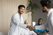 © fizkes - Smiling young male clinician shake hands with happy teammate appreciate for assistance on surgery show support respect on team council. Two doctors partners handshaking making deal reaching agreement